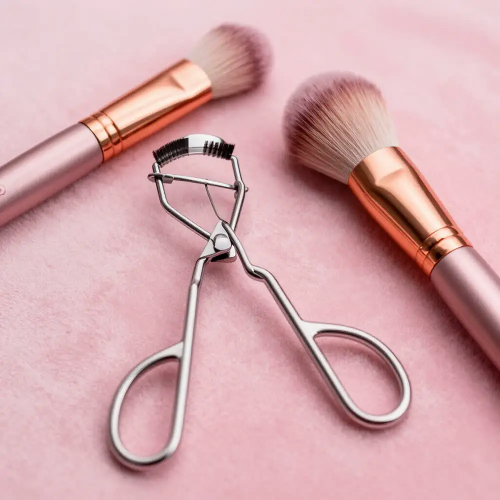Makeup brushes and eyelash curler on a blush background, Cambridge Beauty Academy