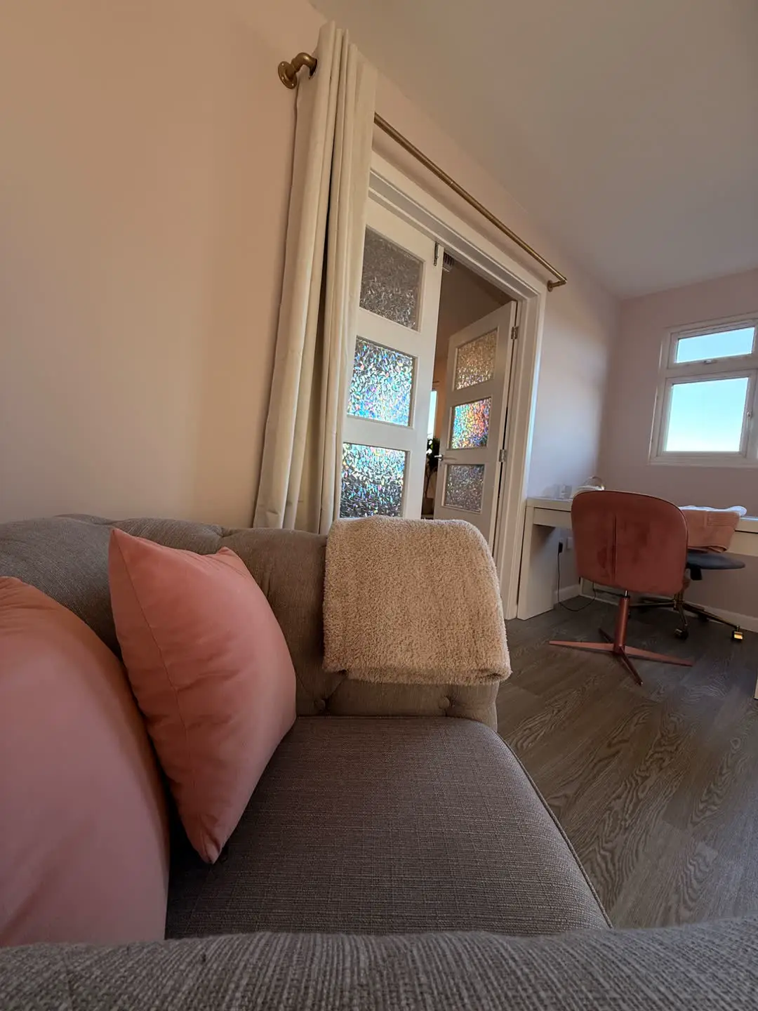 Sitting area at Fabulook Beauty in Arrington, with a sofa, pink cushions and a treatment desk beyond